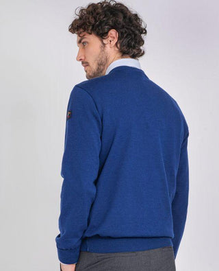 Man wearing blue merino wool V-neck sweater, side view, with a patch on the sleeve
