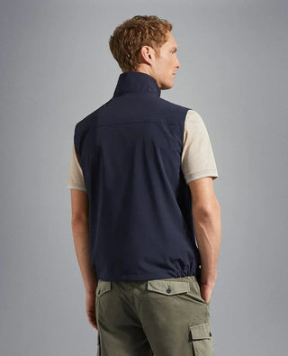 Man wearing a navy blue nylon sleeveless vest and khaki cargo pants, back view