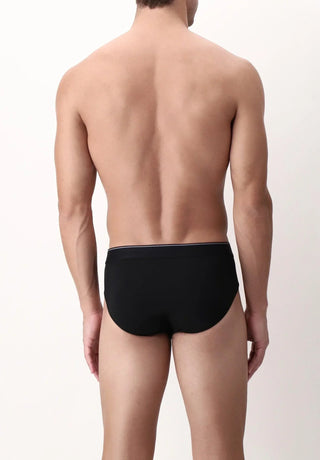 Man wearing black men's briefs underwear, back view against light background